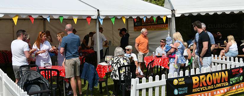 Community event with people socialising under tent.